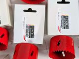 several red hole saws are lined up on a white table