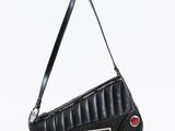 le sac à main noir est posé sur une surface blanche et comporte un bouton rouge