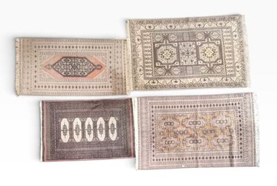 quatre tapis de couleurs et de motifs différents sont disposés sur une surface blanche