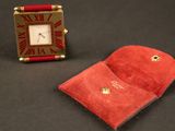 un petit étui rouge et une petite horloge rouge posés sur une surface noire