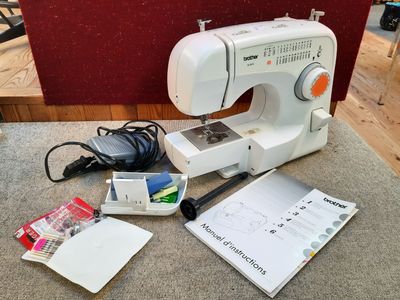 une machine à coudre blanche posée sur une table, à côté d'autres objets