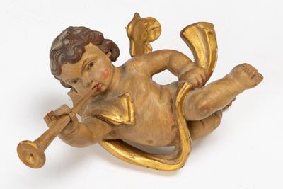 une statue représentant un petit garçon allongé par terre, tenant une trompette