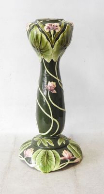 a green vase with pink flowers on it sitting on a table