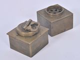 two small metal objects that are sitting on a white surface