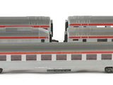 three silver and red train cars sitting next to each other on a white surface
