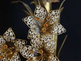 a gold vase with flowers and a candle on it