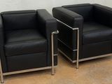 pair of black leather lounge chairs with chrome legs in a room