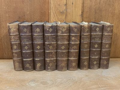 six old books lined up in a row on a wooden surface