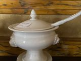 a white bowl with a lid and a spoon on a table