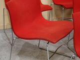 Plusieurs chaises rouges sont alignées en rang dans une pièce