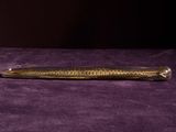 a gold colored pen sitting on a purple surface