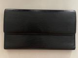 un portefeuille Louis Vuitton noir posé sur une surface blanche