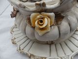 a white vase with a flower on it on a plate