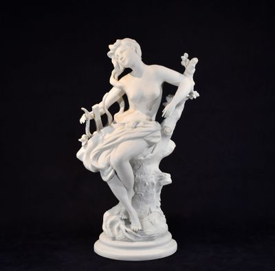 white statue of a woman sitting on a rock with a bird in her hand