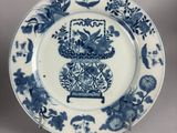 a blue and white plate with a vase of flowers on it