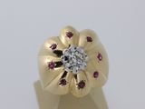 une image représentant une bague en or avec un diamant au centre, entouré de rubis