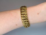 someone is wearing a gold bracelet with a braid design on their arm
