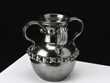 un vase en argent posé sur une table blanche