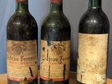 three bottles of wine sit on a wooden table in front of a blue wall