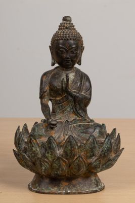 statue of a buddha sitting on a lotus flower on a wooden table