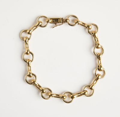 gros plan d'un bracelet en chaîne en or sur fond blanc