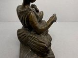 statue d'une femme assise sur un rocher, en train de lire un livre
