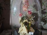 a glass clochet with flowers inside of it on a table