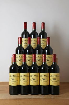 Six bouteilles de vin rouge sont empilées sur une table en bois.