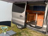 a camper van that is parked in the grass with its door open
