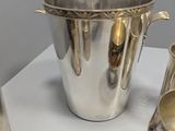 a silver cup and a silver pitcher on a table