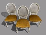 three chairs with cane back cushions and a cane back seat