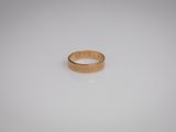 gros plan d'une bague en or sur une surface blanche