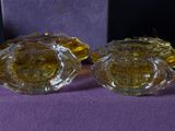 pair of yellow glass ashtrays on a purple cloth