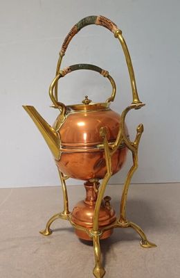 a copper tea kettle on a stand on a table