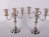trois bougeoirs en argent posés sur une table, sur fond blanc