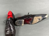 pair of black leather shoes with red soles sitting on a gray surface