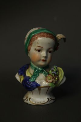 une petite figurine représentant une femme coiffée d'un chapeau