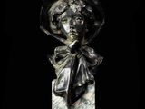 statue of a woman with a hat and bow on a marble block