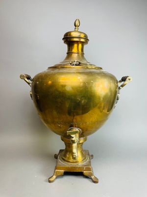 une urne ancienne en laiton posée sur un socle, sur fond blanc