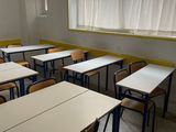tables and chairs in an empty classroom with a window in the background