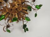 a gold colored chandelier with green leaves and flowers
