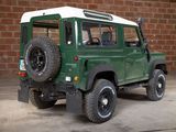 a green and white jeep parked in front of a brick wall