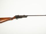 a rifle on a white surface with a wooden handle