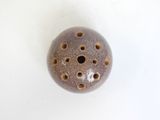 a ceramic object with holes in it on a white surface
