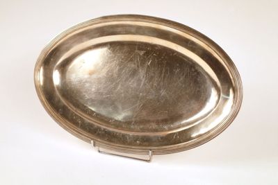 a silver plate on a stand on a white surface