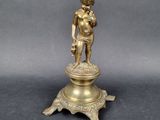 brass figurine of a boy holding a bird on a pedestal