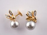 deux paires de boucles d'oreilles en perles et diamants posées sur un fond blanc