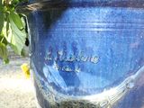 a blue vase with a bird on it sitting on the ground