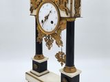 a clock that is sitting on a stand on a white surface