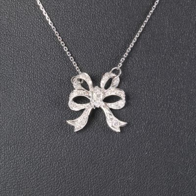 a close up of a necklace with a bow on it